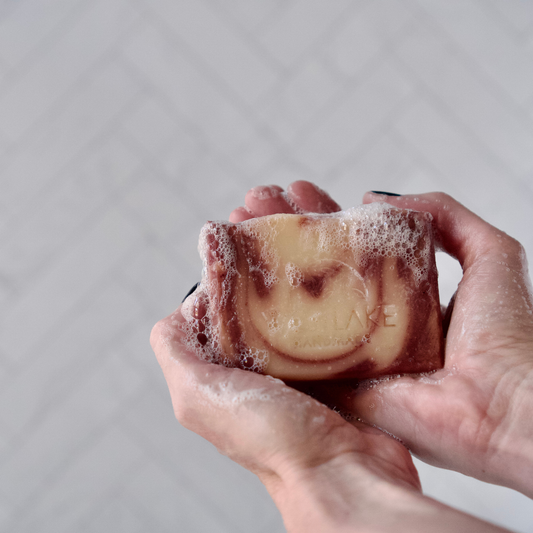 Hand holding a bar of Westlake Handmade soap against a plain background
