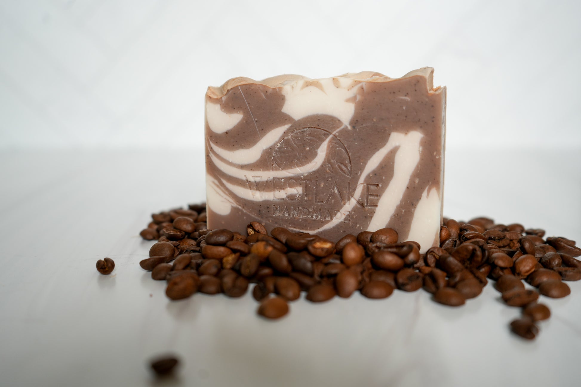 Westlake Handmade bar of coffee soap with a swirled design on top of coffee beans.