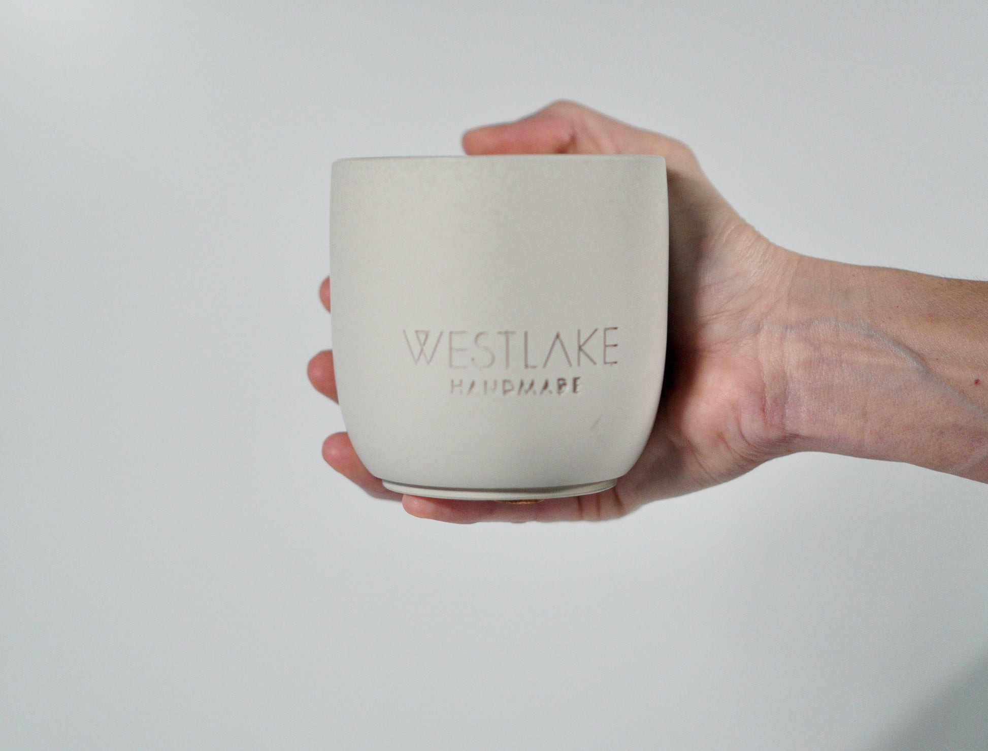 Hand holding a Westlake Handmade concrete jar against a plain background