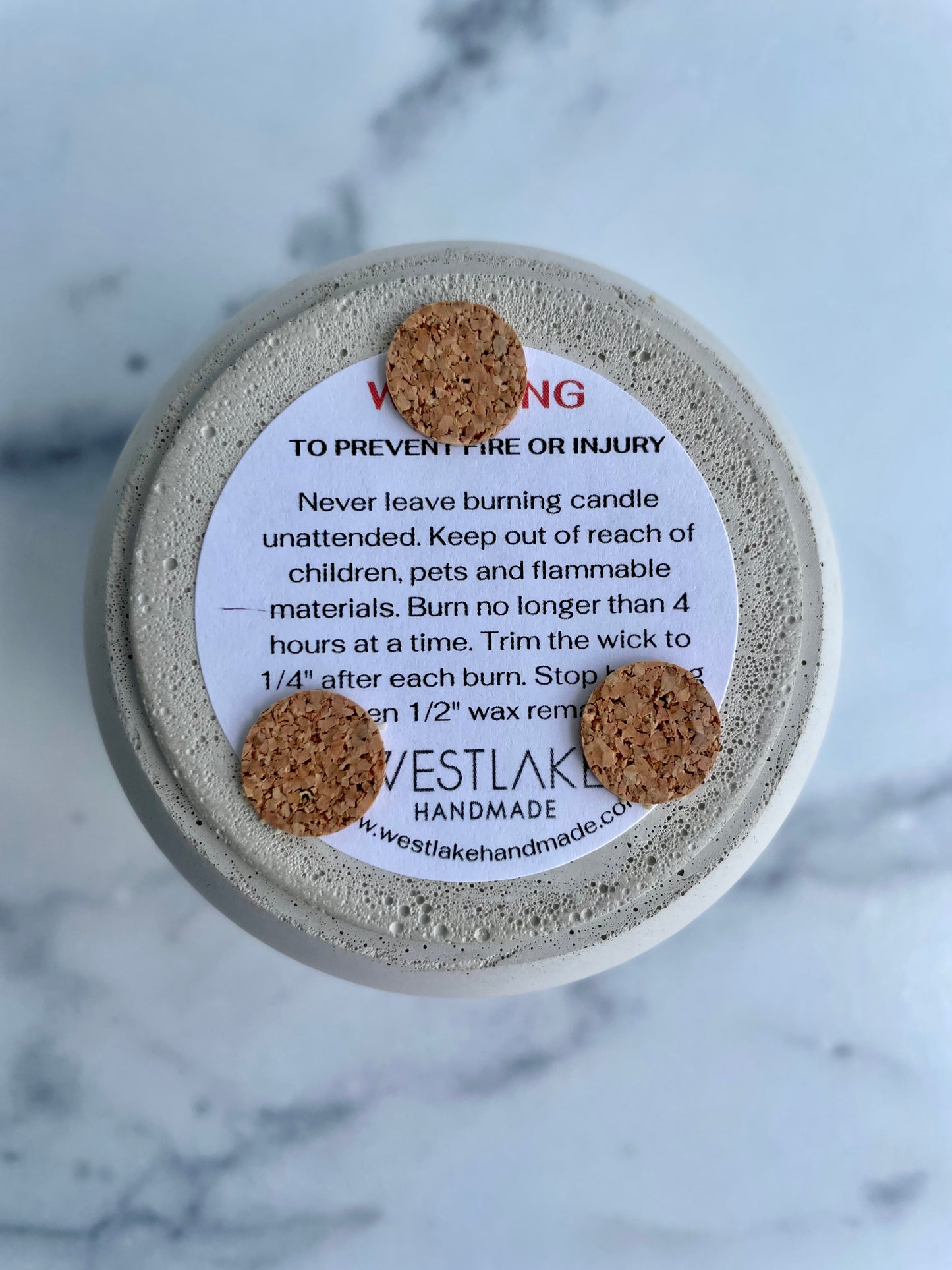 Candle bottom with cork bumpers and Westlake Handmade label on a marble background