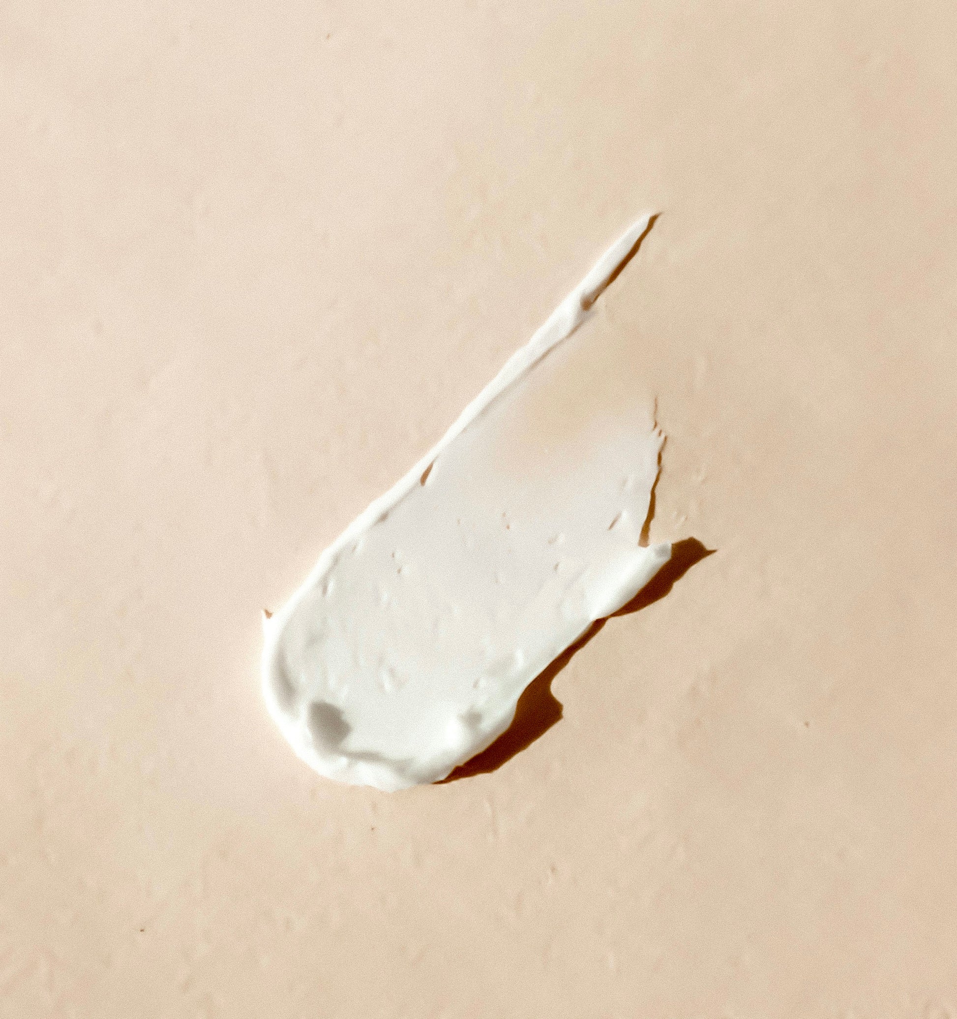 White cream smear on a beige background