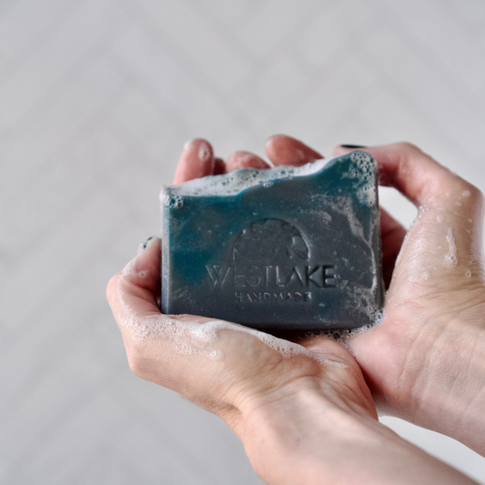 Hand holding a bar of Westlake Handmade soap against a neutral background