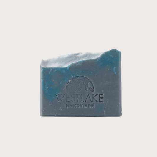 Blue and black bar of soap with 'Westlake Handmade' branding on a light gray background