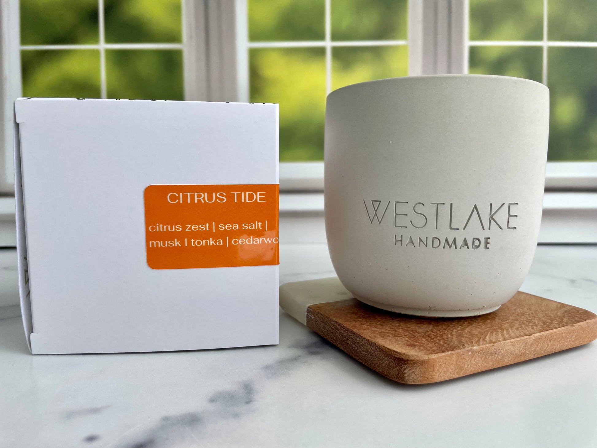Westlake Handmade concrete candle on a wooden coaster, next to a box labeled 'Citrus Tide'.