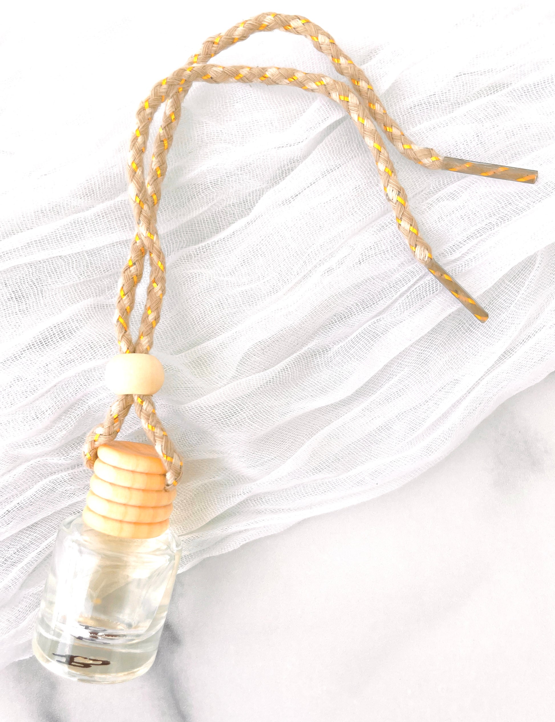 Small travel diffuser bottle with a wooden cap and decorative string on a white background