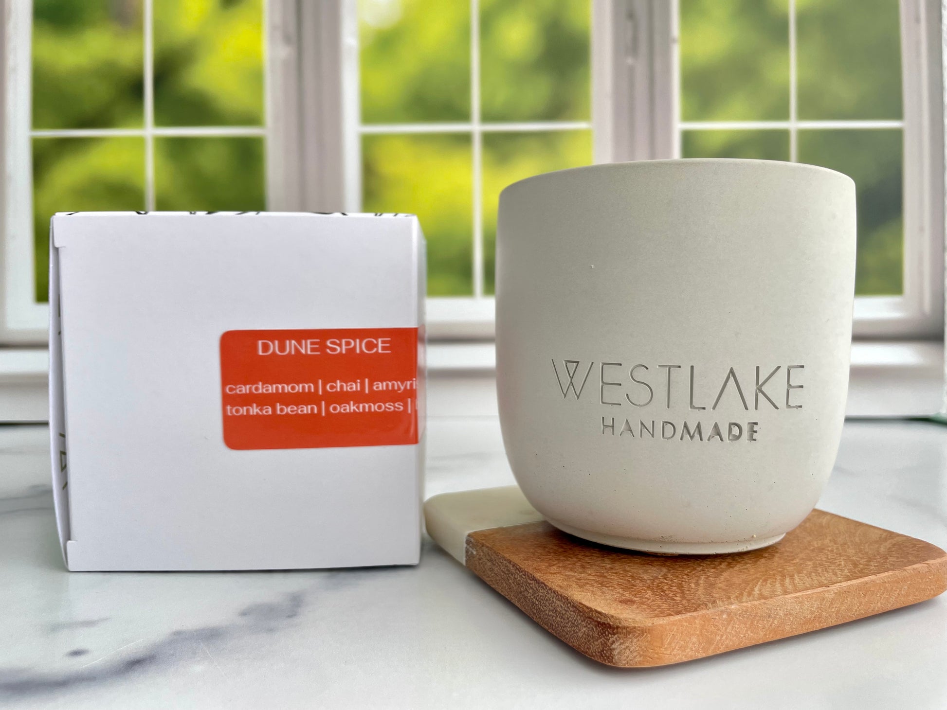 Westlake Handmade concrete candle on a wooden coaster, next to a box labeled 'Dune Spice'.