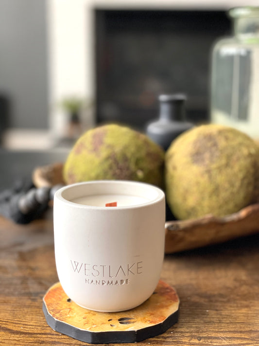 Westlake candle on a wooden coaster with a blurred background