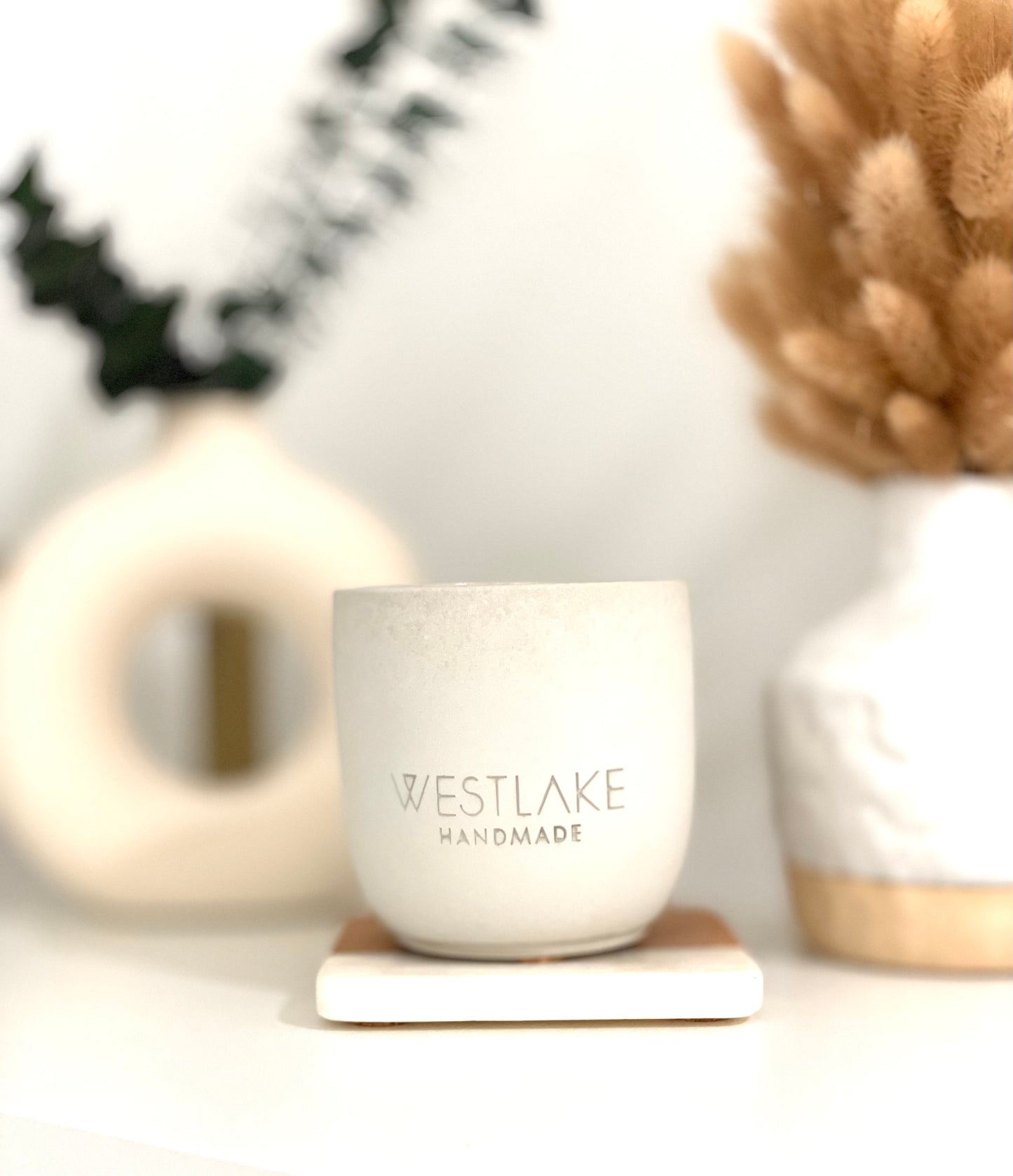 Westlake Handmade concrete candle on a blurred background of decorative items.