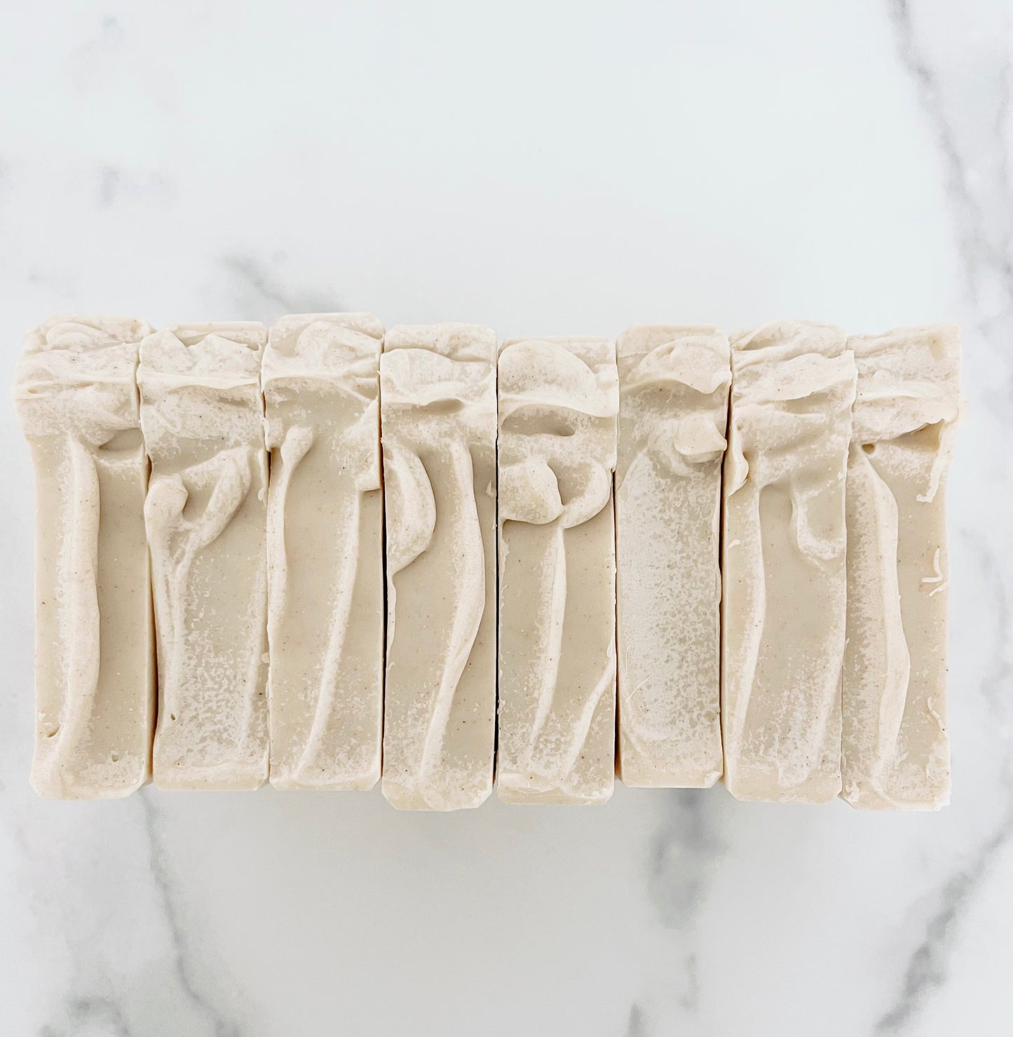 Five bars of soap with textured surfaces on a marble background