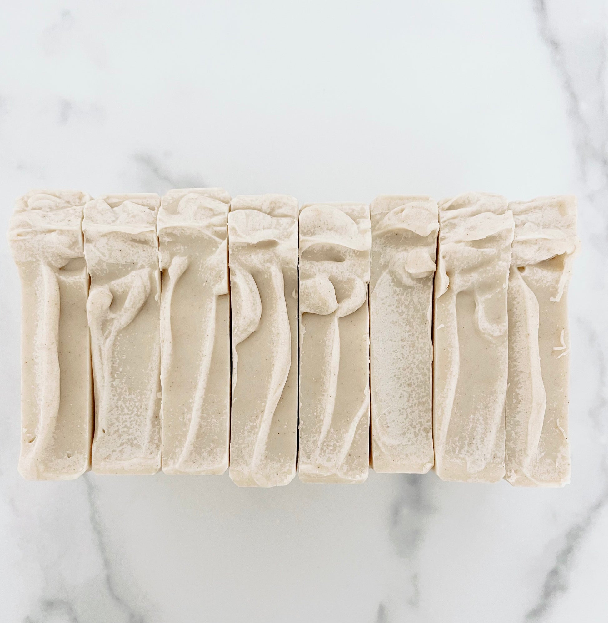 Five bars of soap with textured surfaces on a marble background