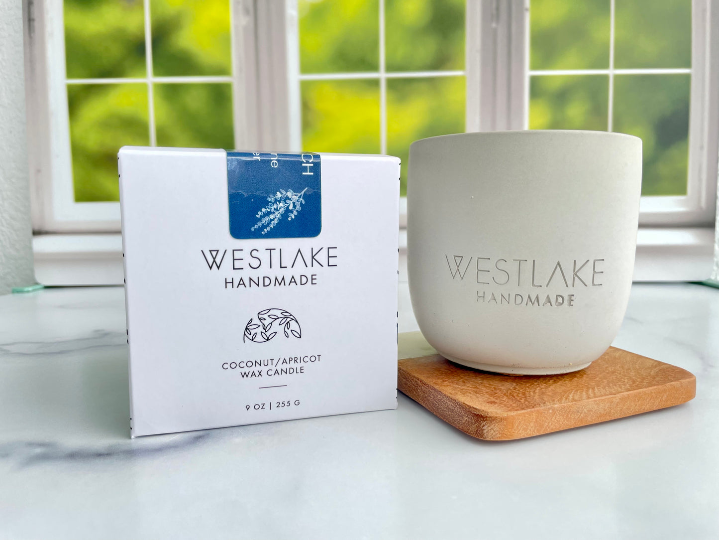 Westlake Handmade candle and packaging on a marble surface with a window in the background