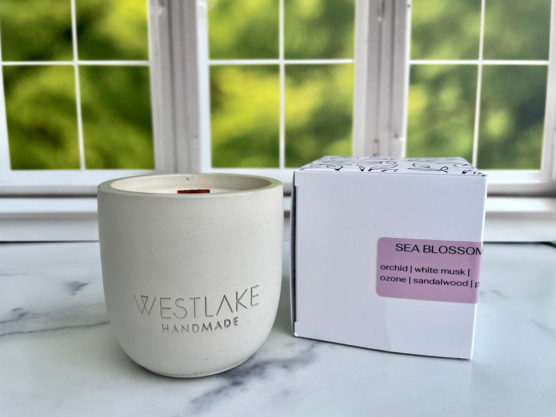 Westlake Handmade candle and packaging on a marble surface with a window in the background
