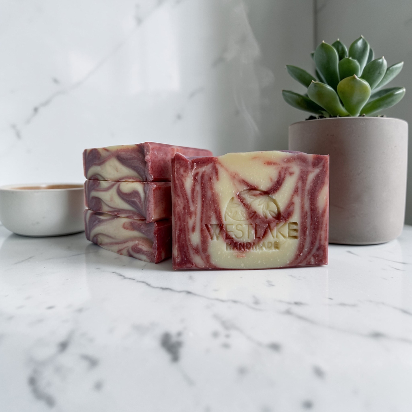 Marbled soap bars with 'Westlake Handmade' branding on a marble surface with a succulent plant in the background.
